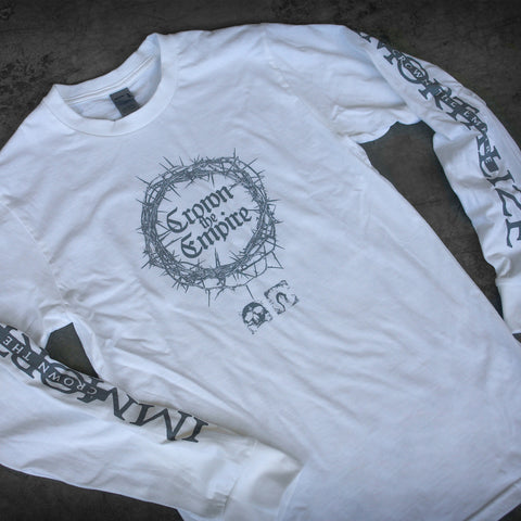 Crown The Empire white long-sleeve shirt with band name inside a circular crown of thorns on the chest, plus decorative text and symbols on both sleeves. Made from soft ring-spun cotton in a modern classic fit.