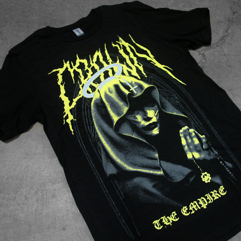 angled image of a black tee shirt on a concrete background. tee has a full body print. in yellow at the top says crown, with an image of a nun with a halo with praying hands holding a crown the empire cog necklace below, and the word empire at the bottom